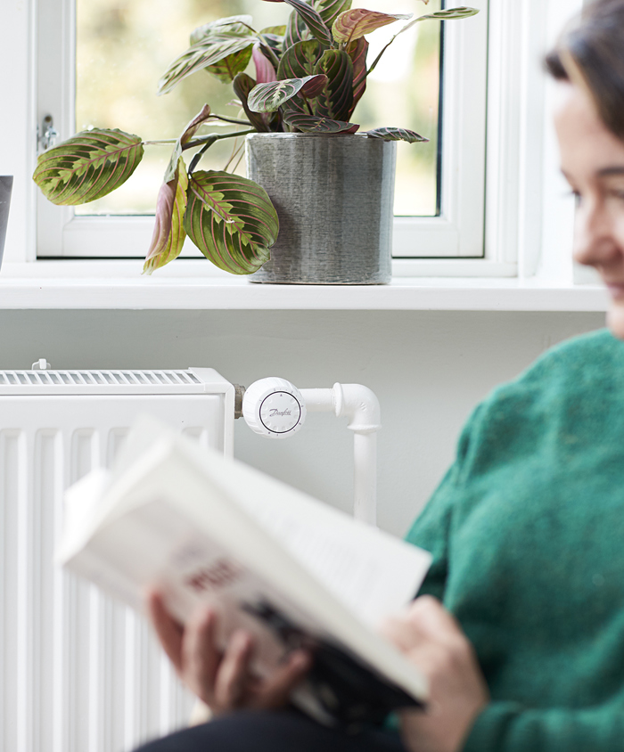 Kvinde læser foran radiator