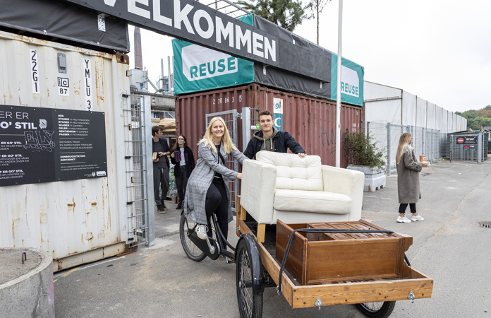 Ungt par kører på ladcykel med møbler fra REUSE